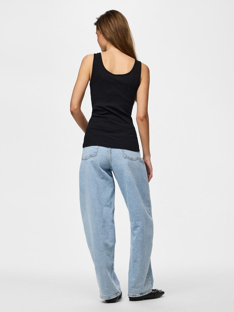 Woman wearing a black tank top and light blue jeans on a white background