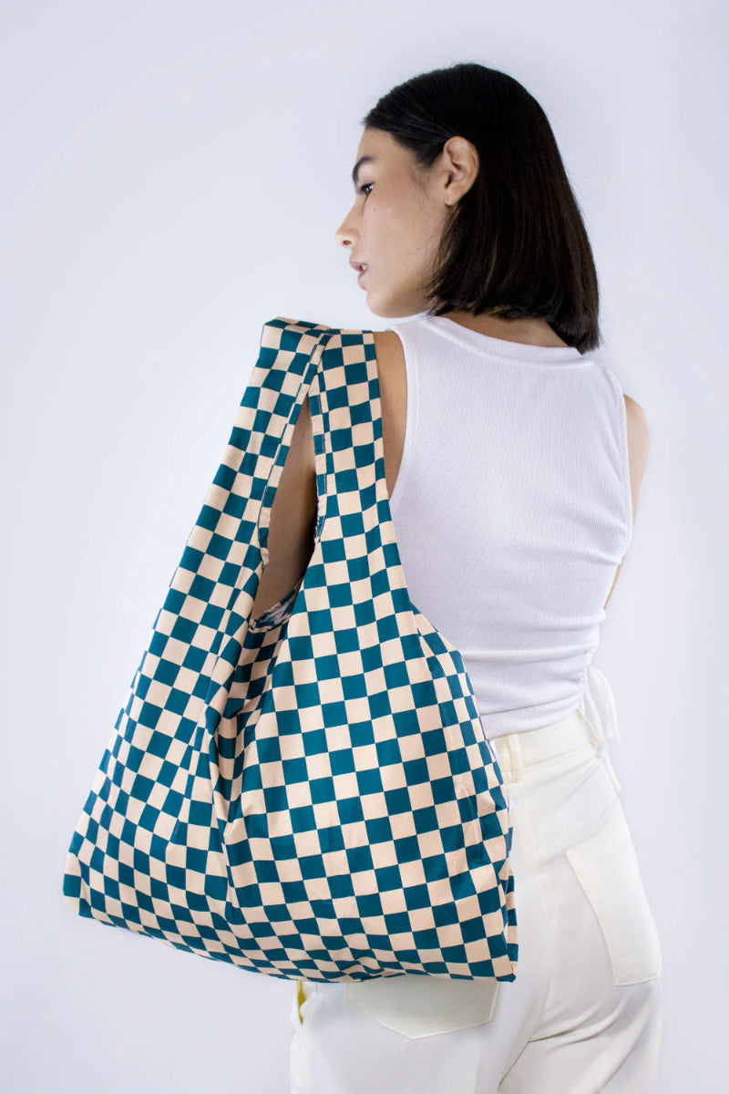 Woman carrying a large checkered bag on a white background