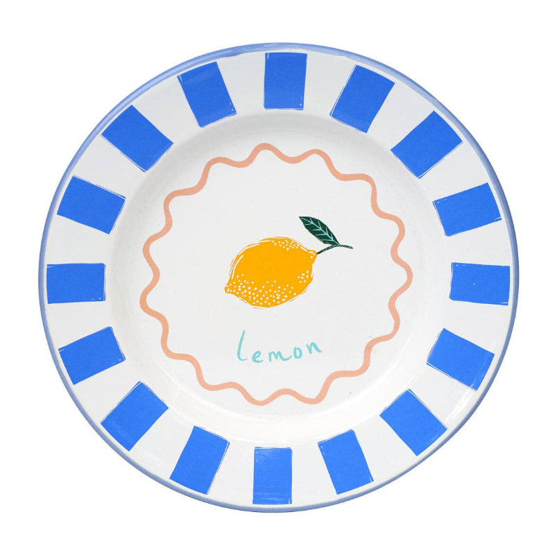 White plate with blue rim and lemon design in center on white background