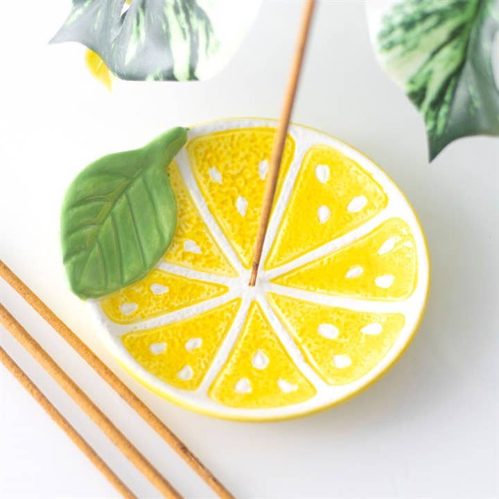 Decorative incense holder shaped like a lemon slice with a green leaf on a white background.