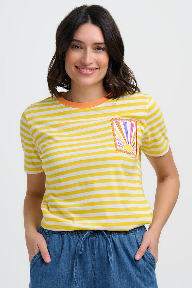 Woman wearing a yellow and white striped t-shirt with a colorful rainbow design on a plain background