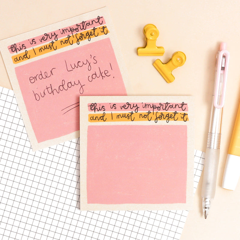 Pink notepad with humorous text and a yellow clip on a grid background