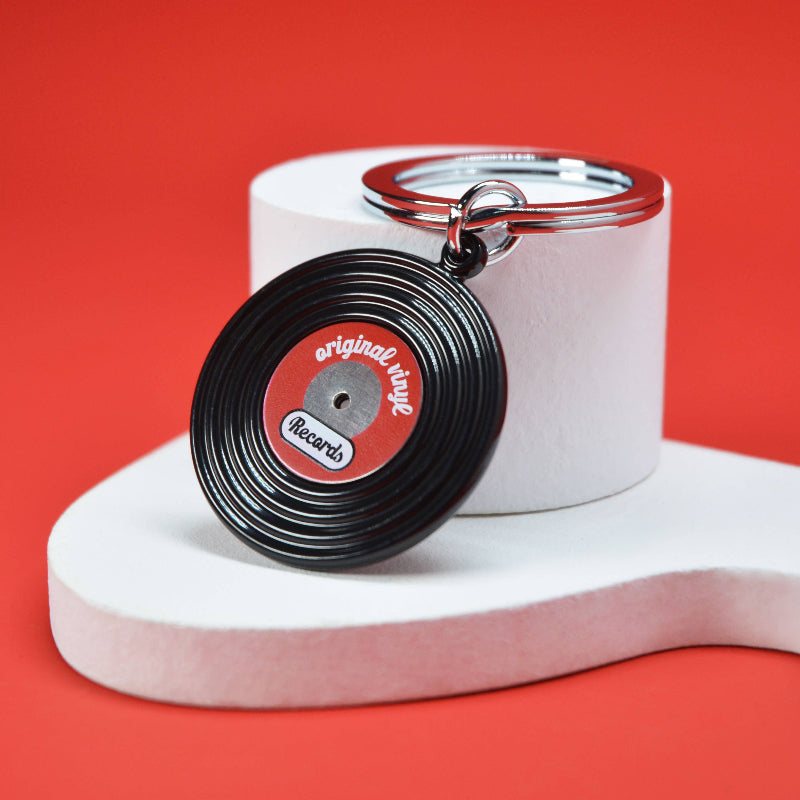 Record-shaped keychain with 'original vinyl' design on a red background