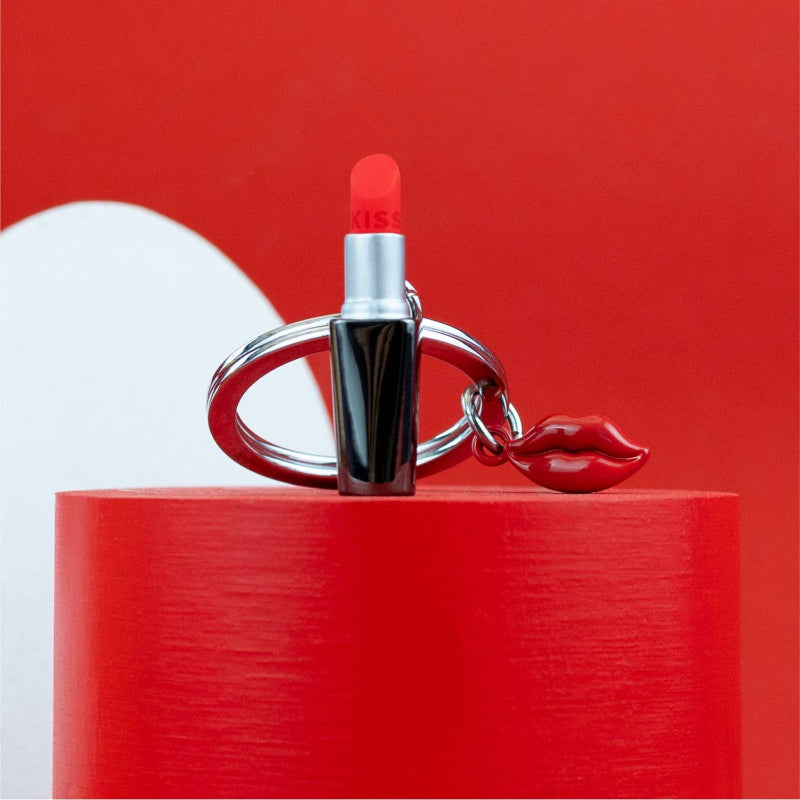 Lipstick-shaped keychain on a red platform with a red background