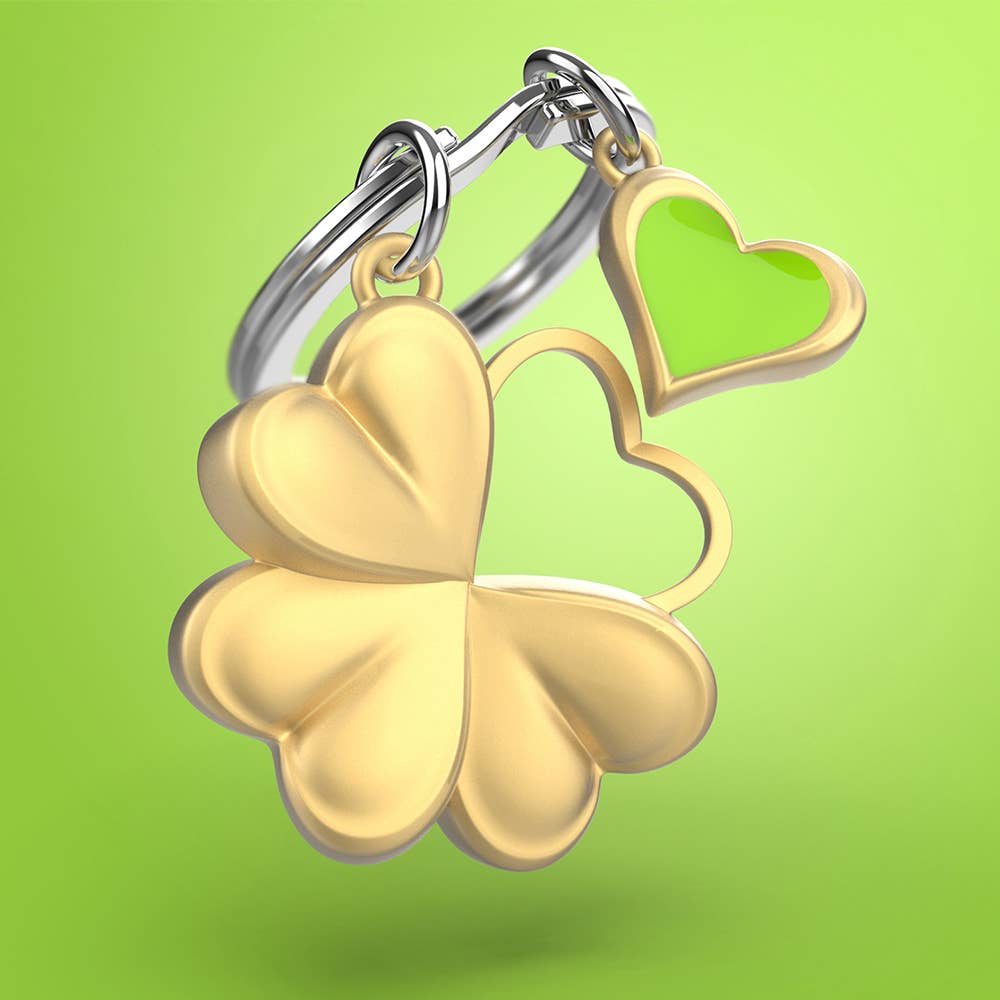 Gold four-leaf clover keychain with a heart charm on a green background