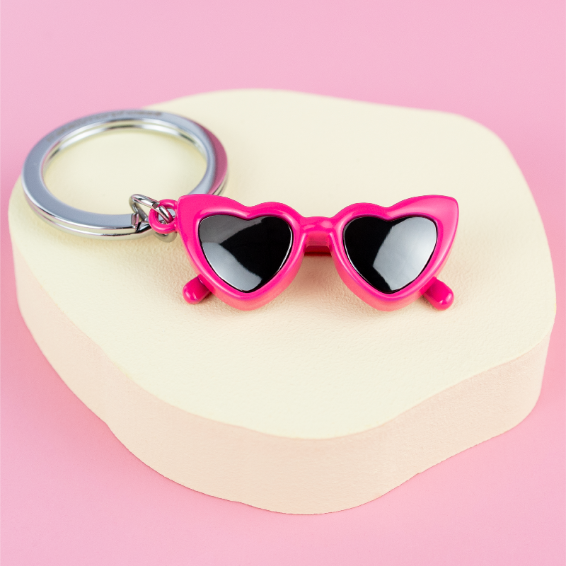 Pink heart-shaped sunglasses keychain on a pink background