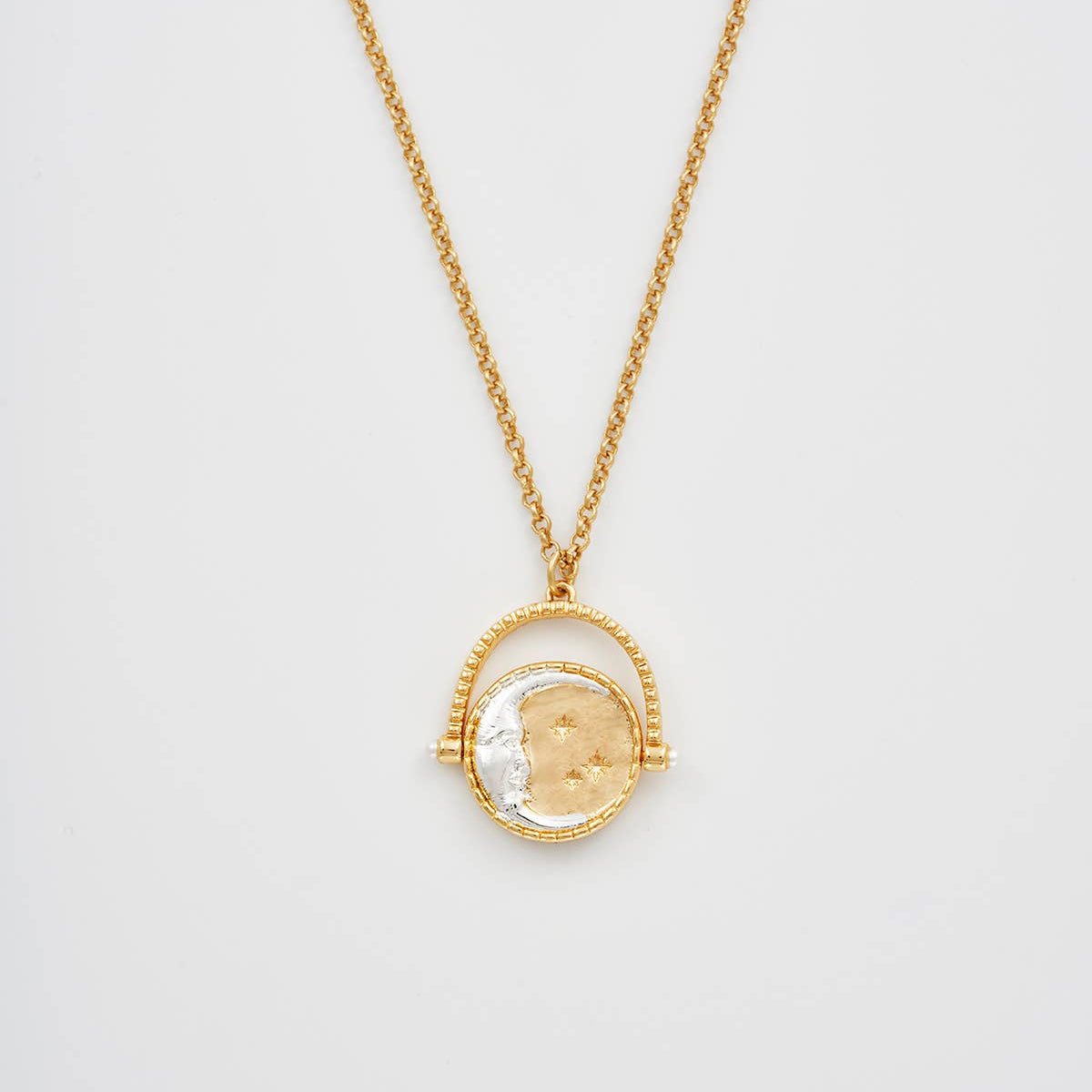 Gold necklace with a round pendant on a light gray background