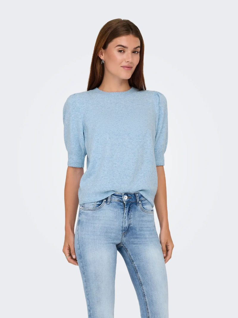 Woman wearing a light blue sweater and jeans on a white background