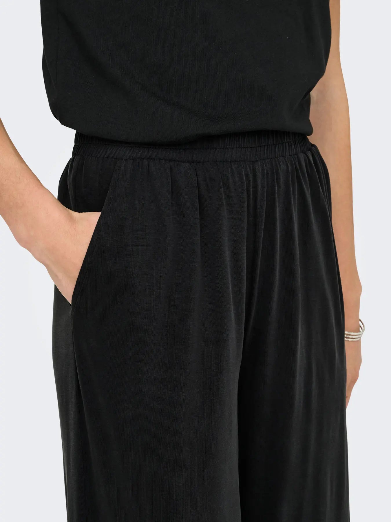 Person wearing black pants on a plain background