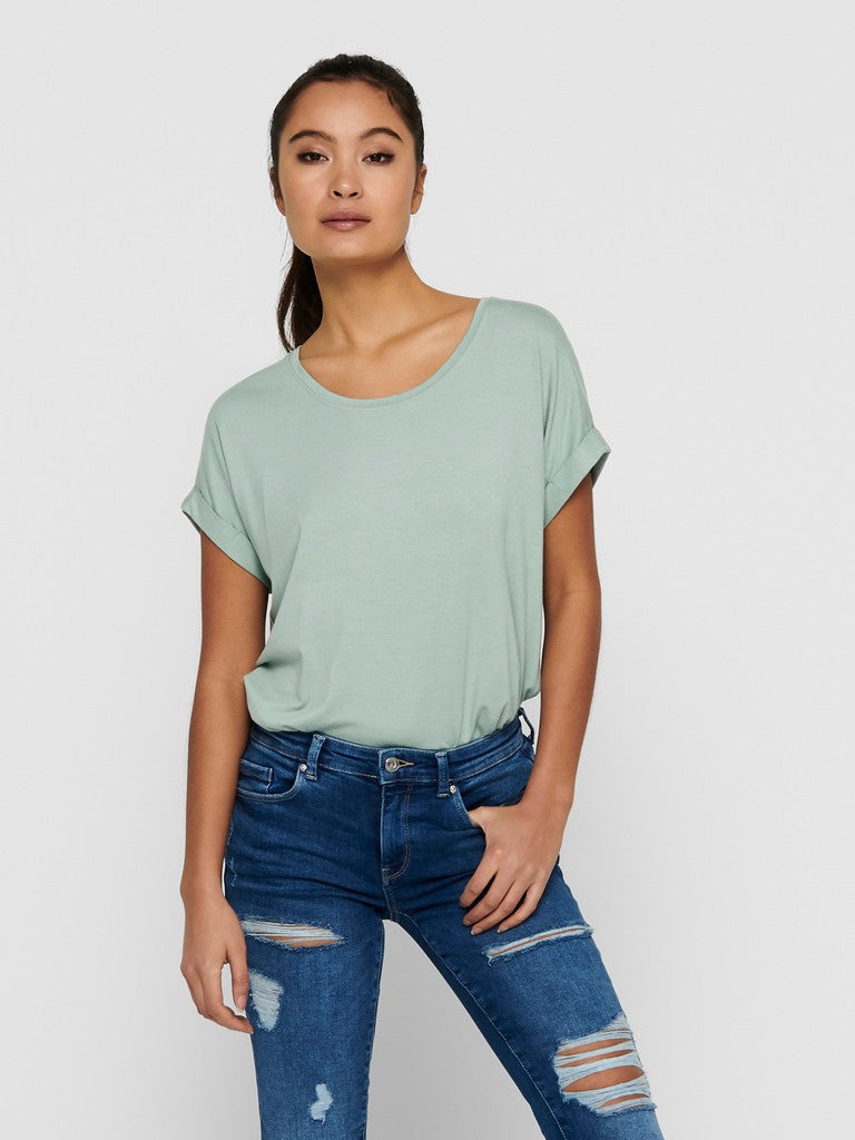 Woman wearing a light green t-shirt and blue jeans on a white background