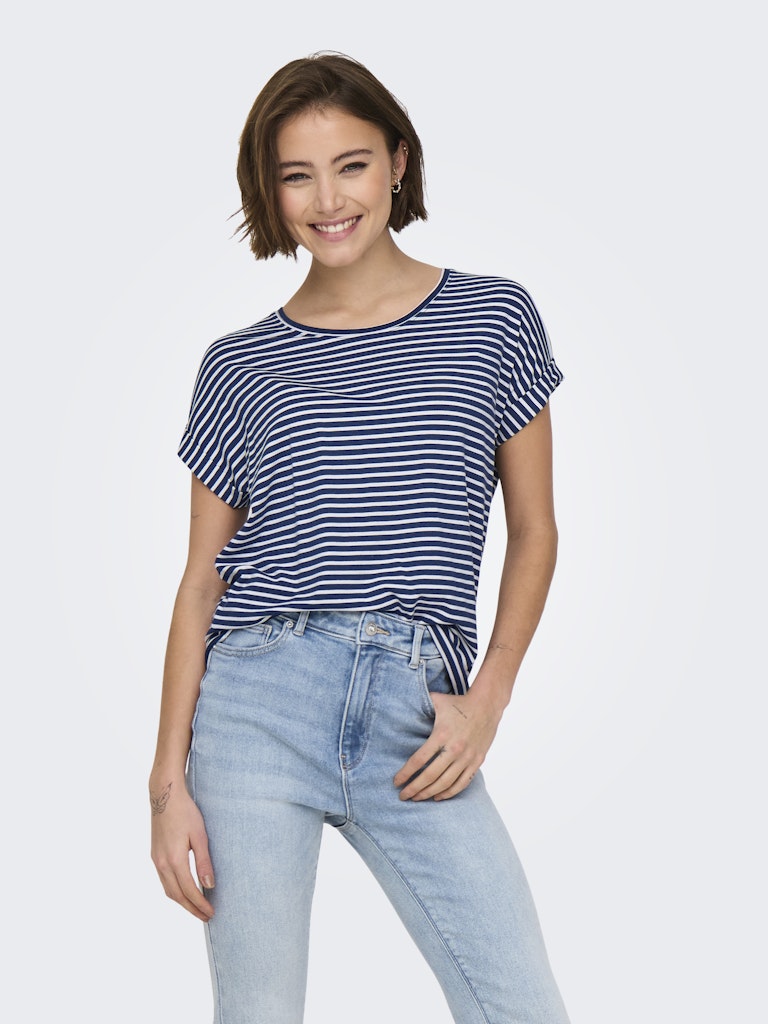 Woman wearing a striped navy and white top and light blue jeans on a plain background