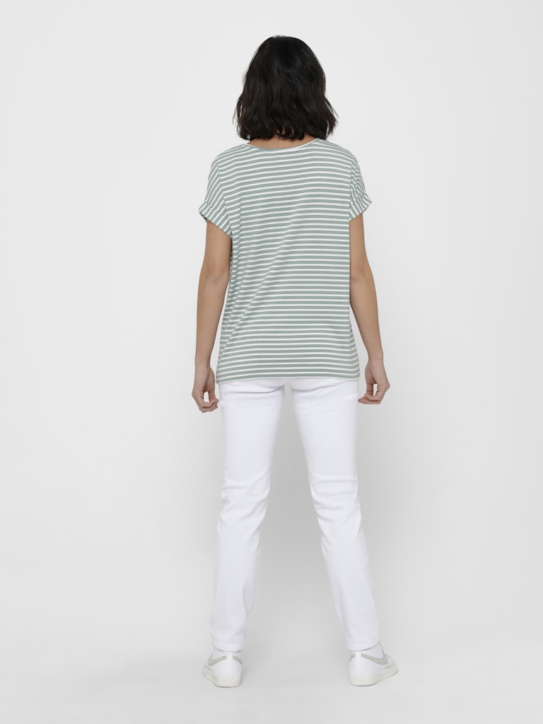Person wearing a striped shirt and white pants on a plain background