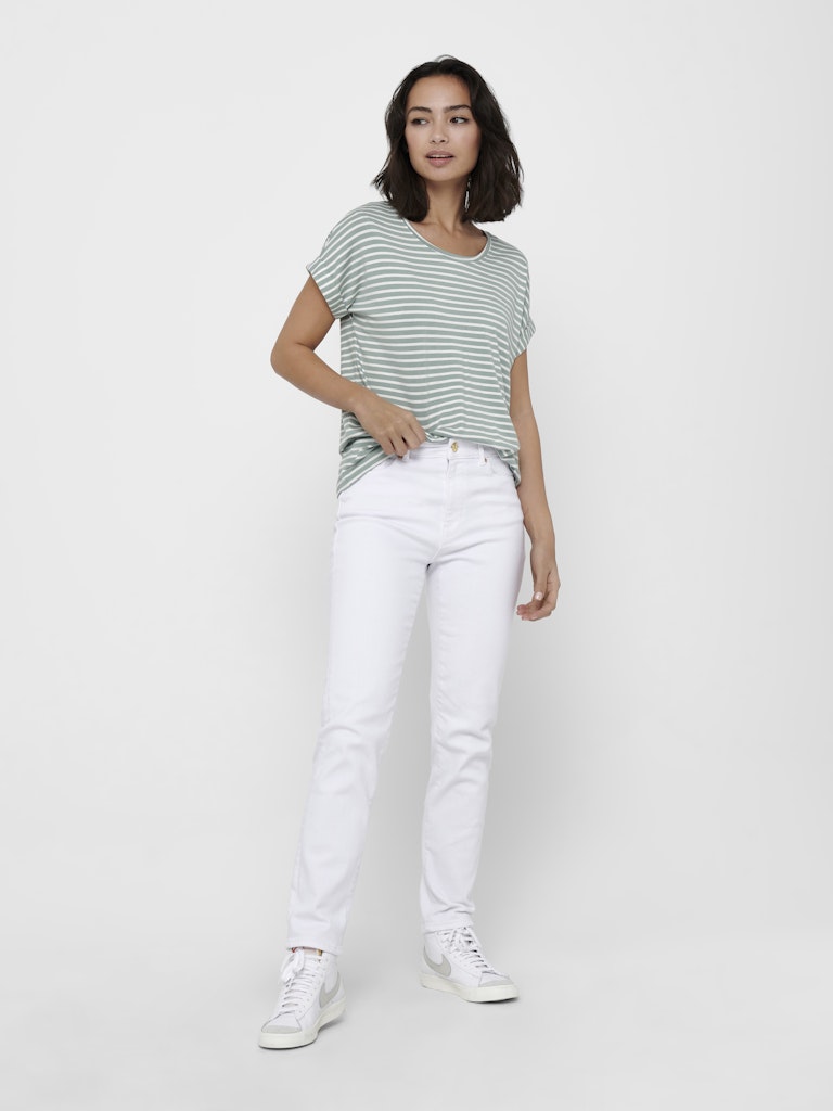 Woman wearing a striped shirt and white pants on a plain background