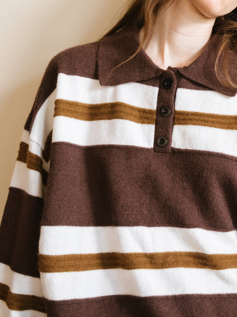 Close-up of a person wearing a brown, white, and gold striped sweater.