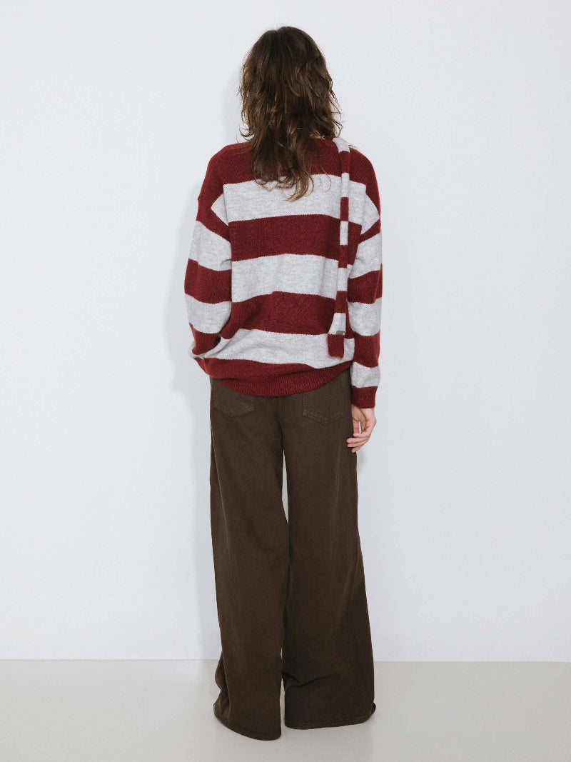 Person wearing a red and white striped sweater and brown pants against a white background