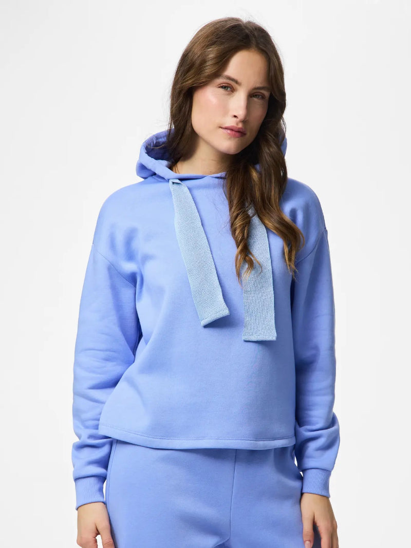 Woman wearing a Pieces Chilli Glitter Hoodie Hydrangea Blue with a towel draped over her shoulders on a white background