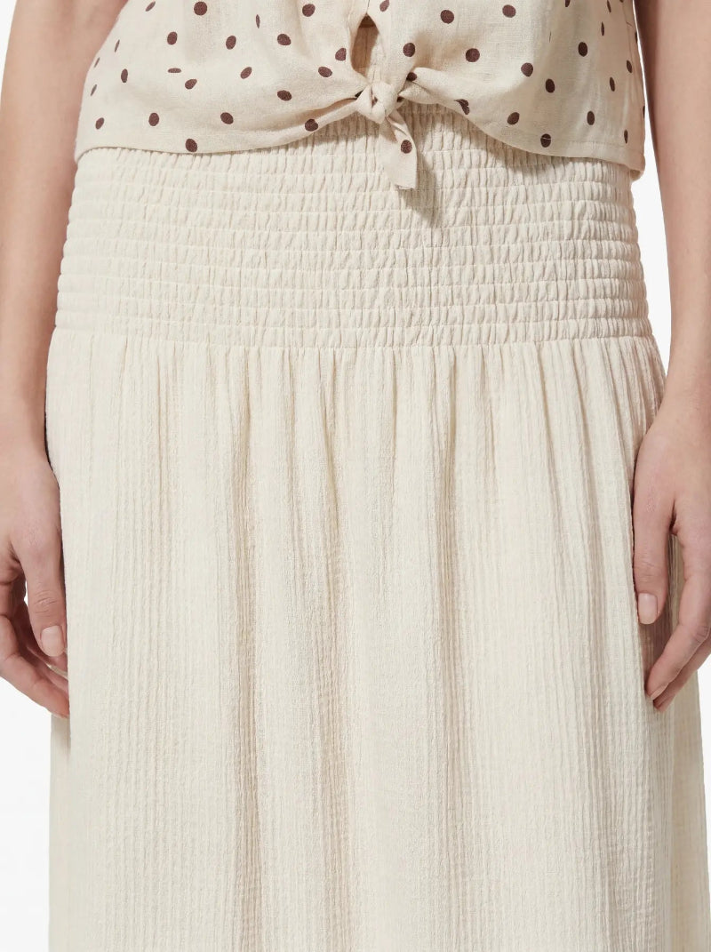 Beige polka dot top and pleated skirt set on a plain background