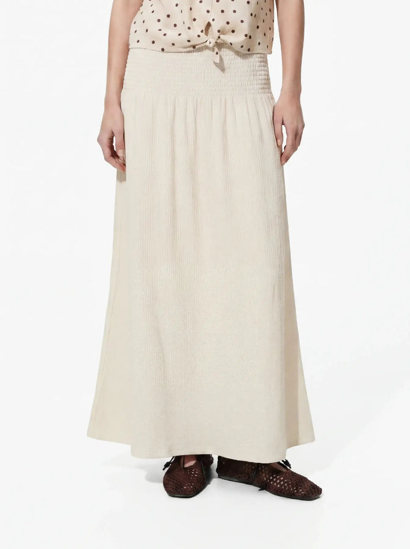 A person Pieces Fess SKirt wearing a long cream skirt with a smock waistband plain