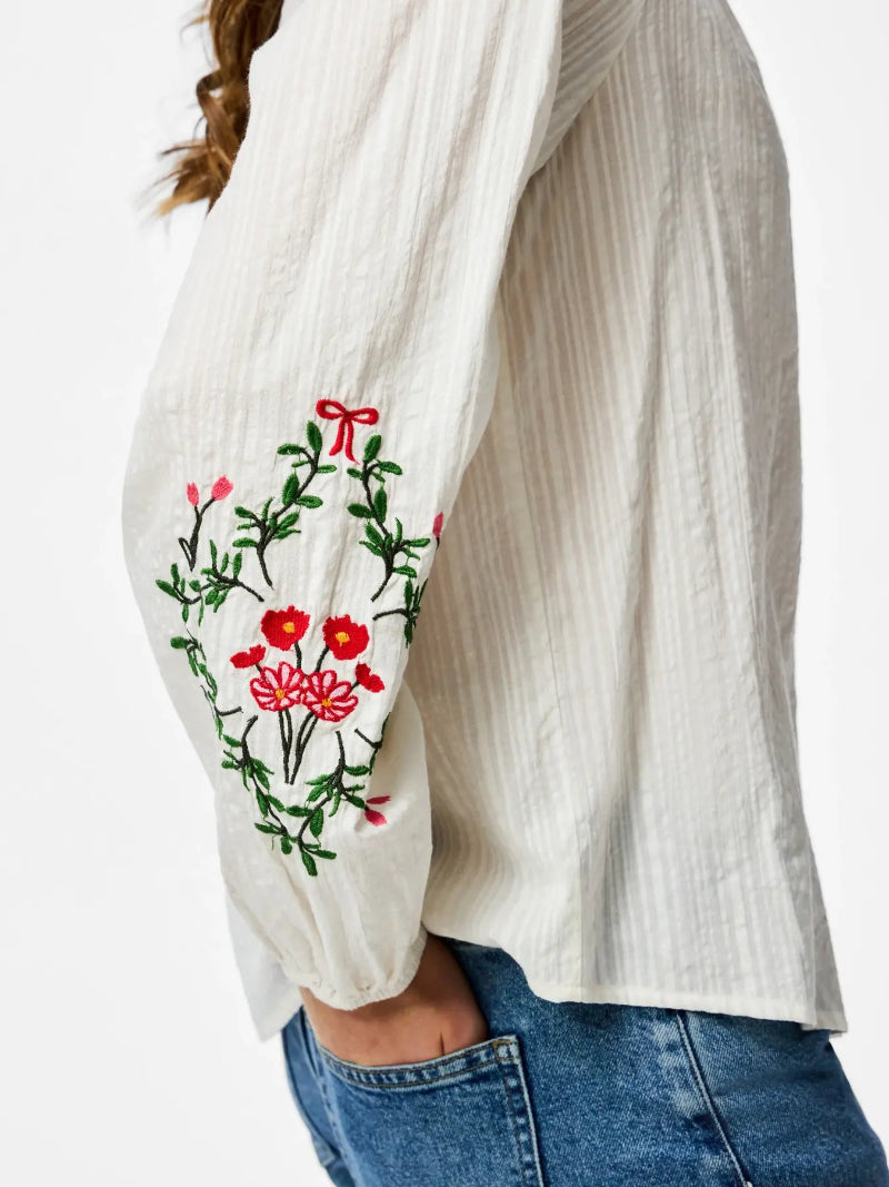 White blouse with floral embroidery on a white background
