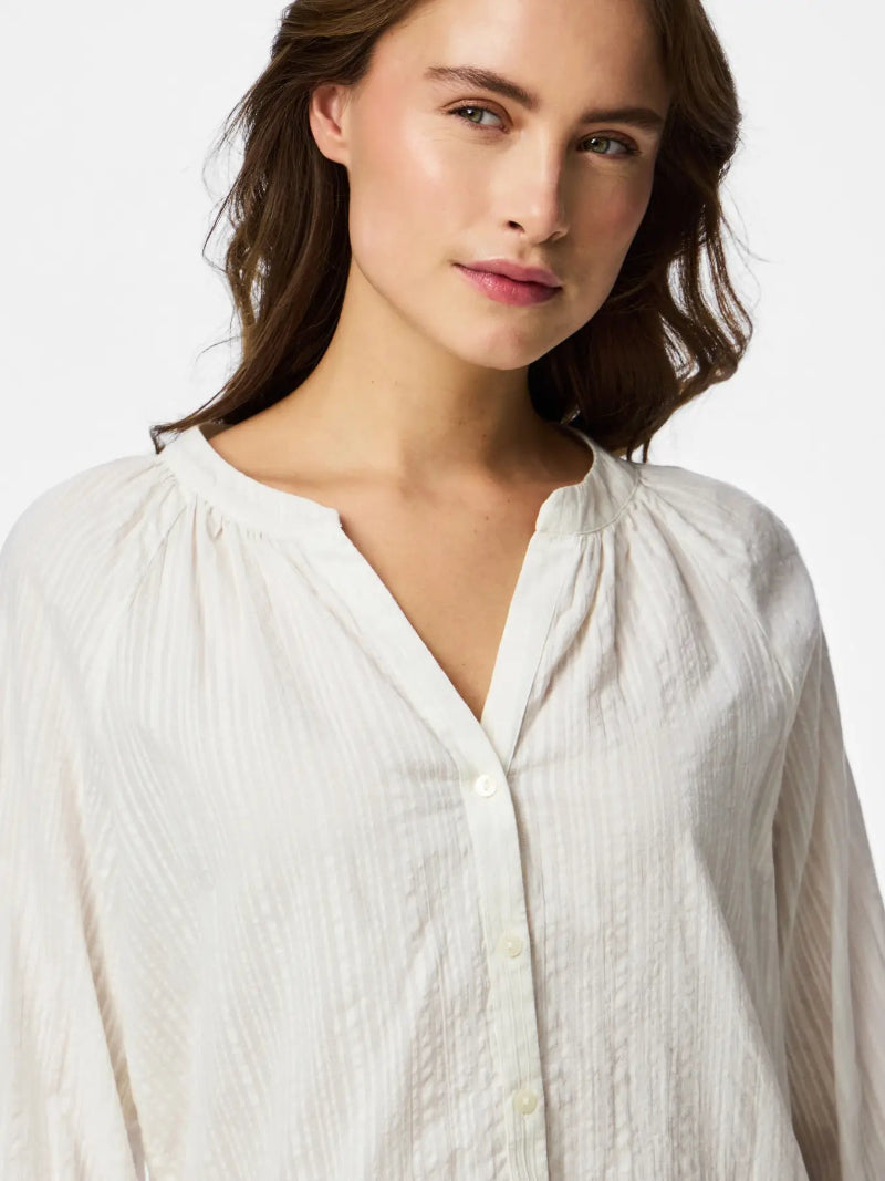 Woman wearing a white blouse against a plain background