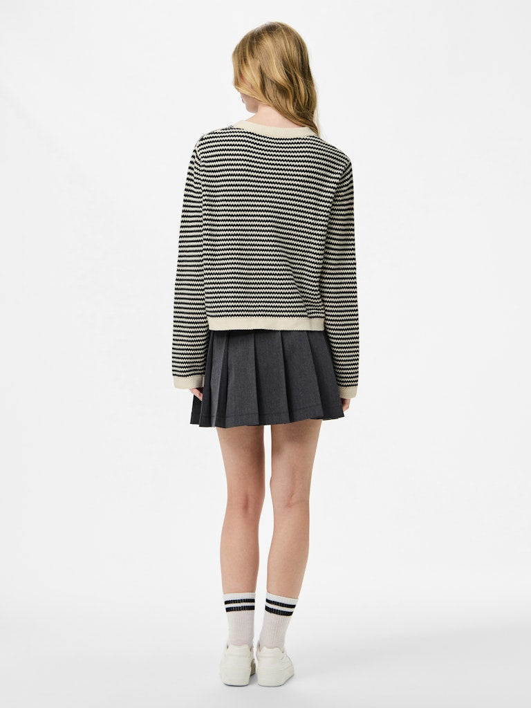 Person wearing a striped sweater and pleated skirt on a white background