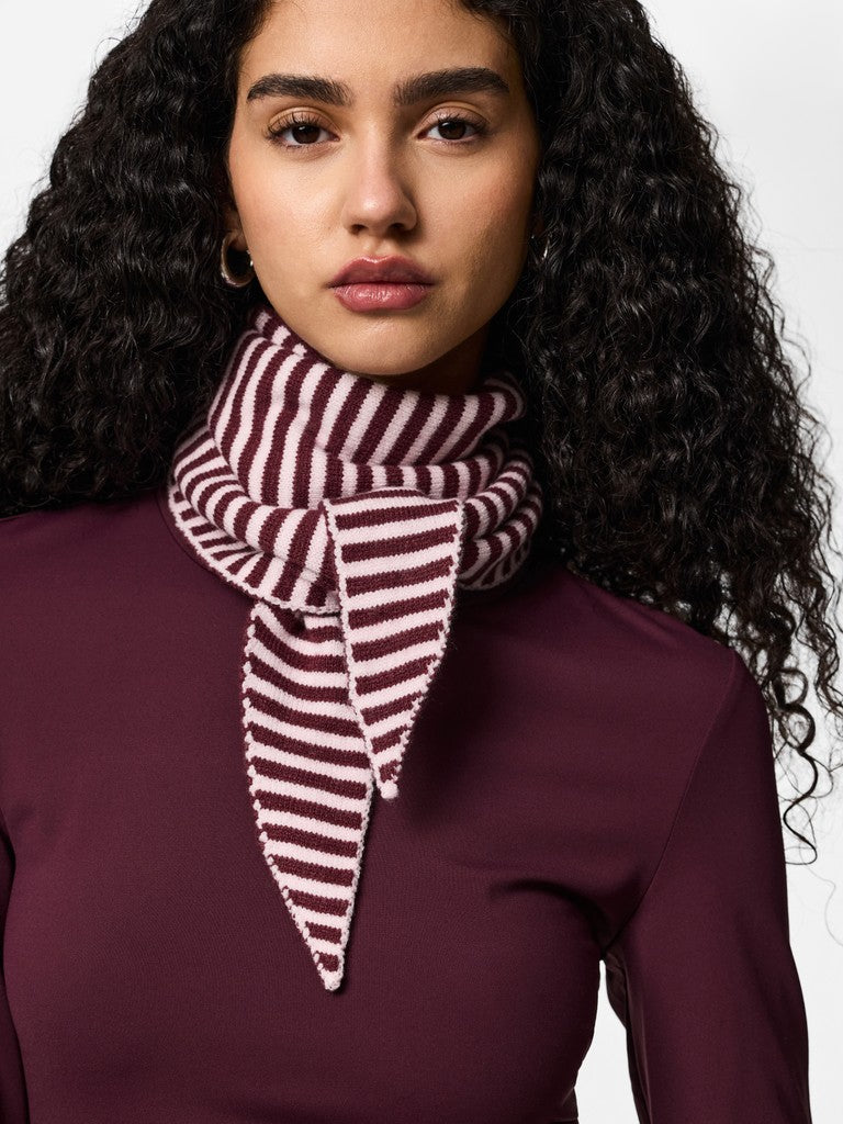 Woman wearing a burgundy and white striped scarf against a plain background