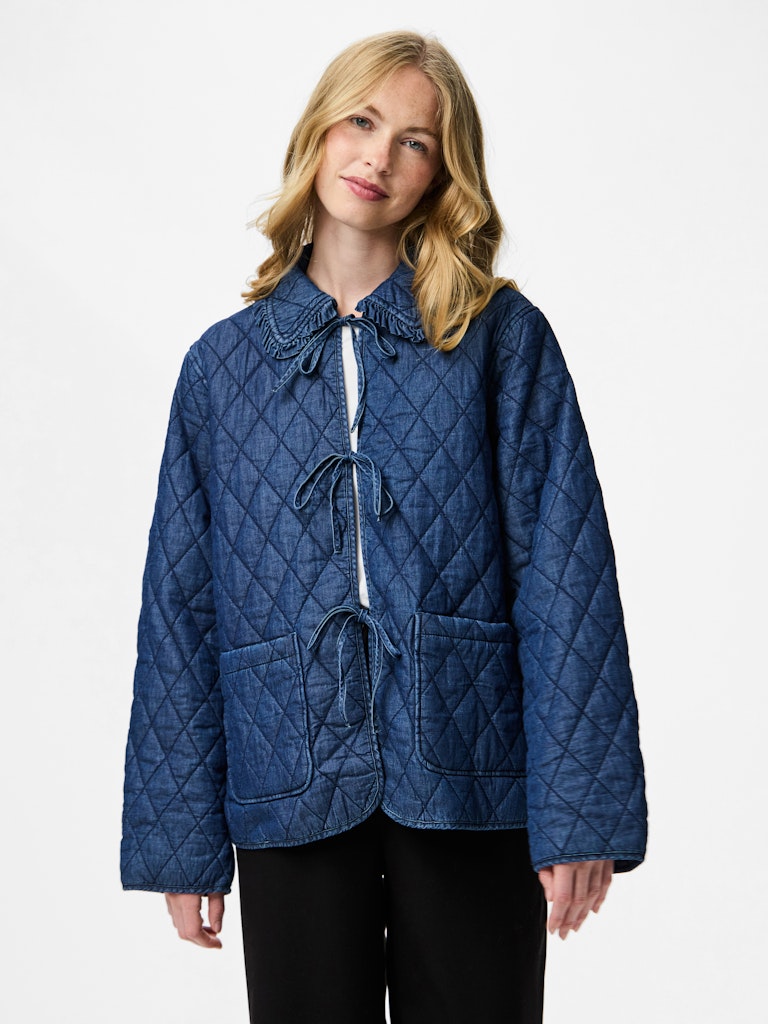 Woman wearing a blue quilted jacket on a white background