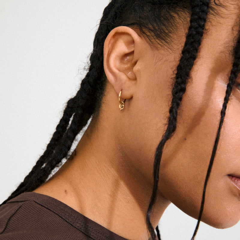 Close-up of a person wearing a Pilgrim Alaia Earrings Gold-plated with braided hair on a neutral background