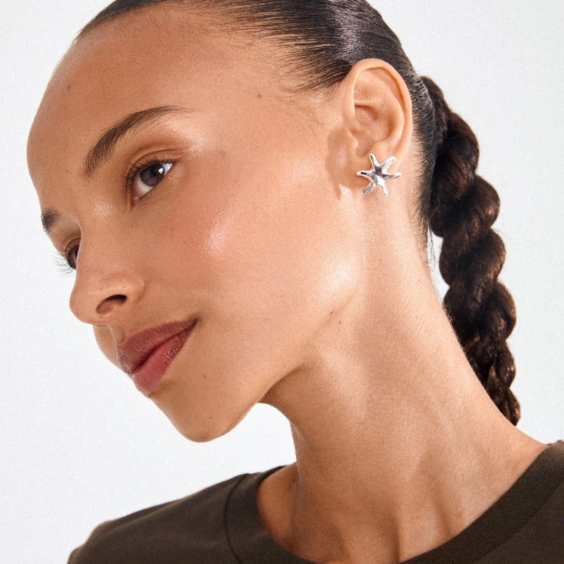 A woman wearing silver earrings on a white background