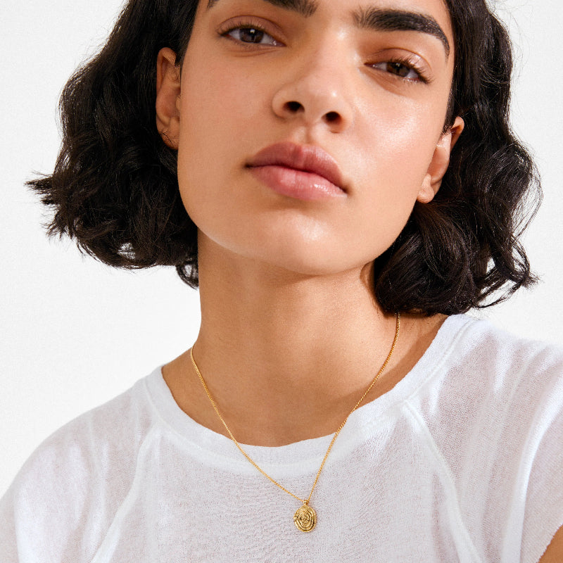 Person wearing a gold necklace with a white background