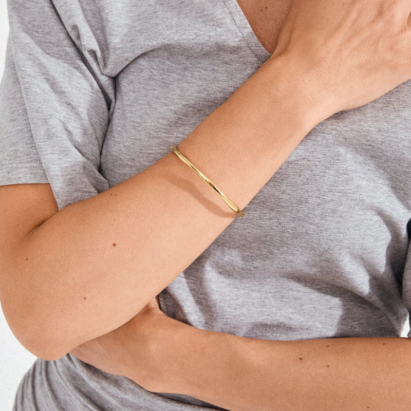 Gold bracelet on a person wearing a gray shirt