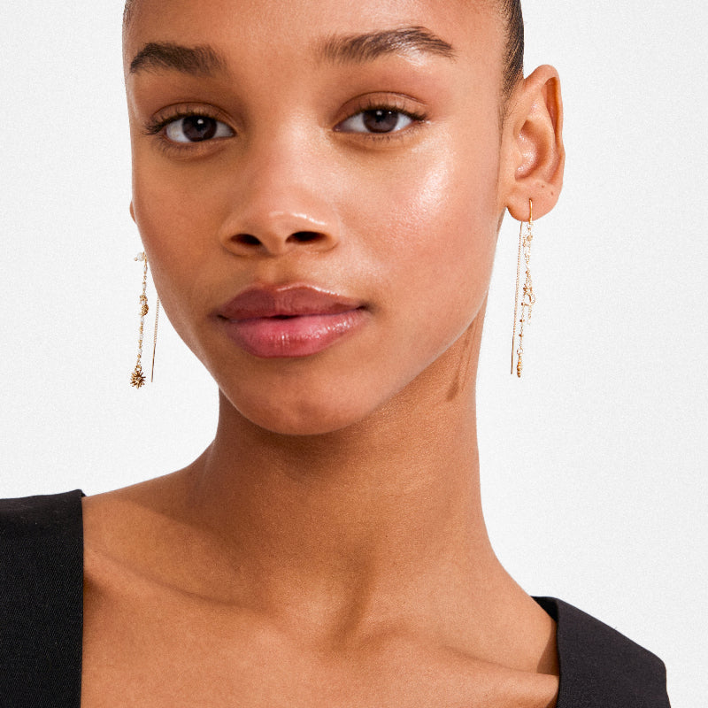 A person wearing long earrings on a white background