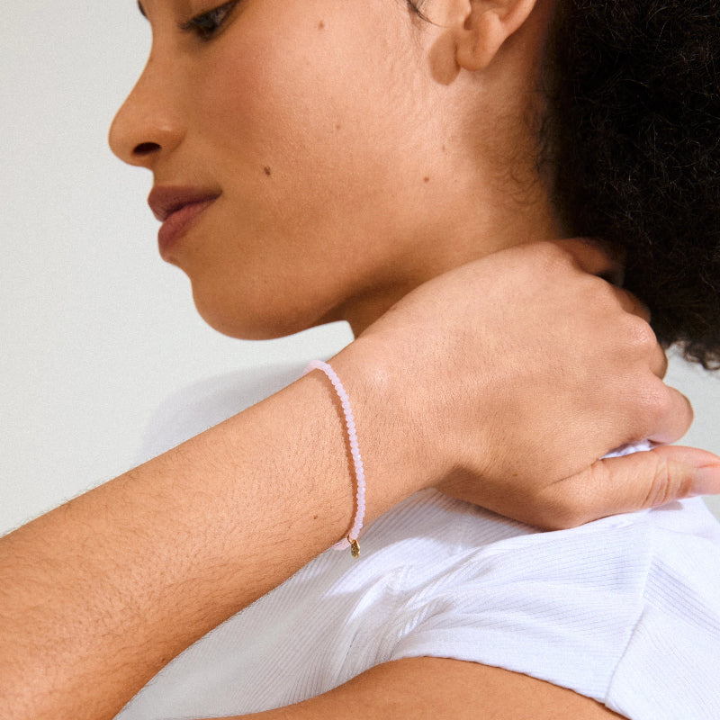 Woman wearing a pink bracelet on a light background