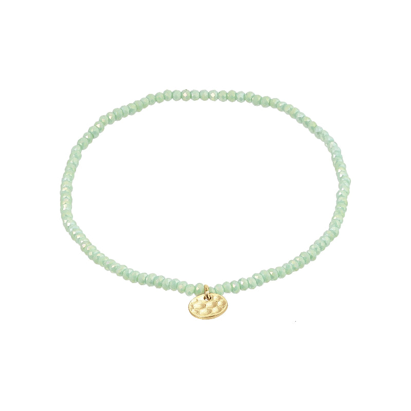 Green beaded bracelet with a gold charm on a white background