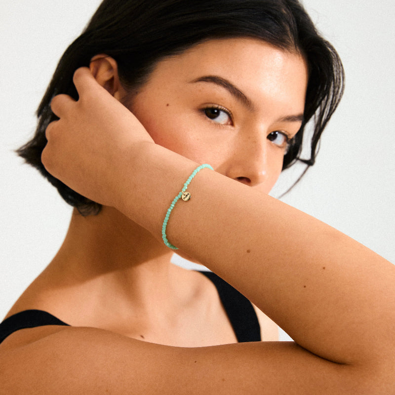 Woman wearing a turquoise bracelet on a plain background