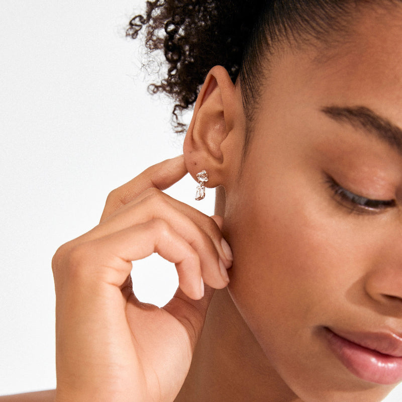 Close-up of a woman wearing a silver earring on a neutral background