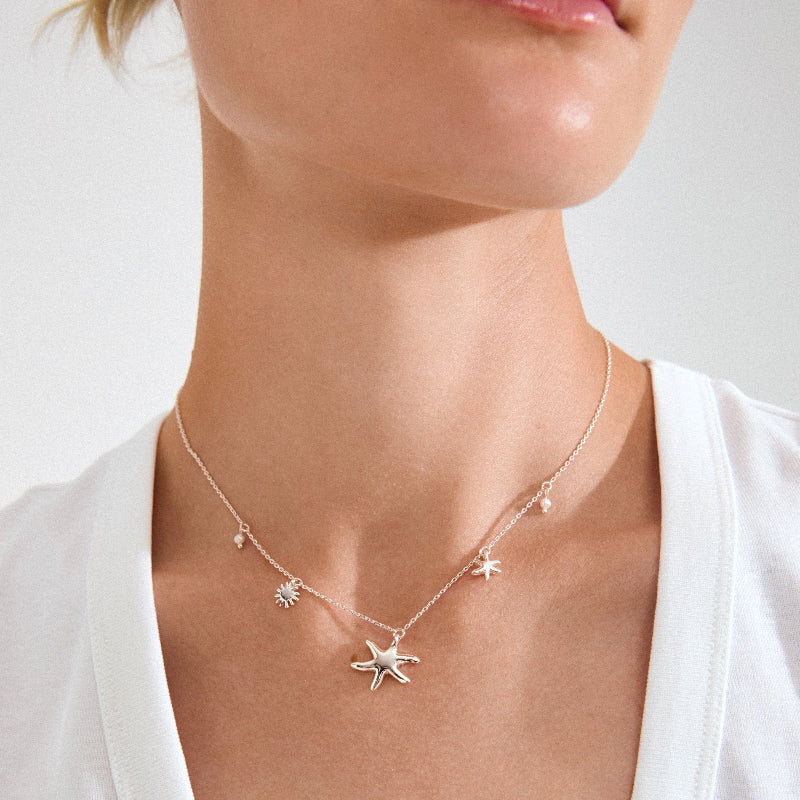Starfish necklace worn by a person on a plain background