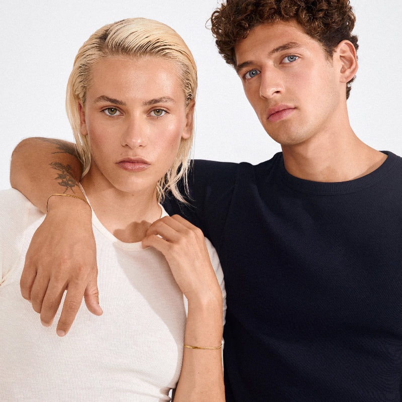 Two people standing close together with a plain background