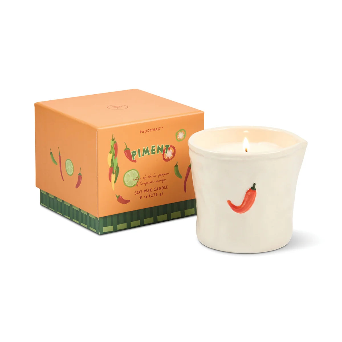 Candle with chili pepper design next to its packaging on a white background