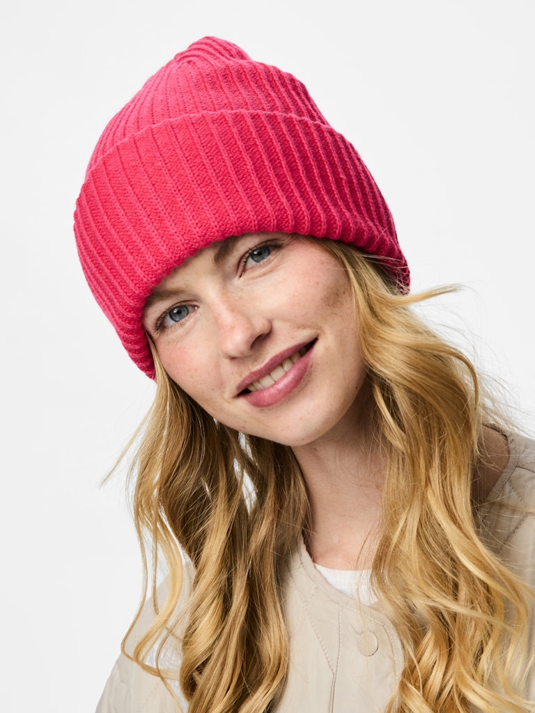 Woman wearing a pink beanie against a white background