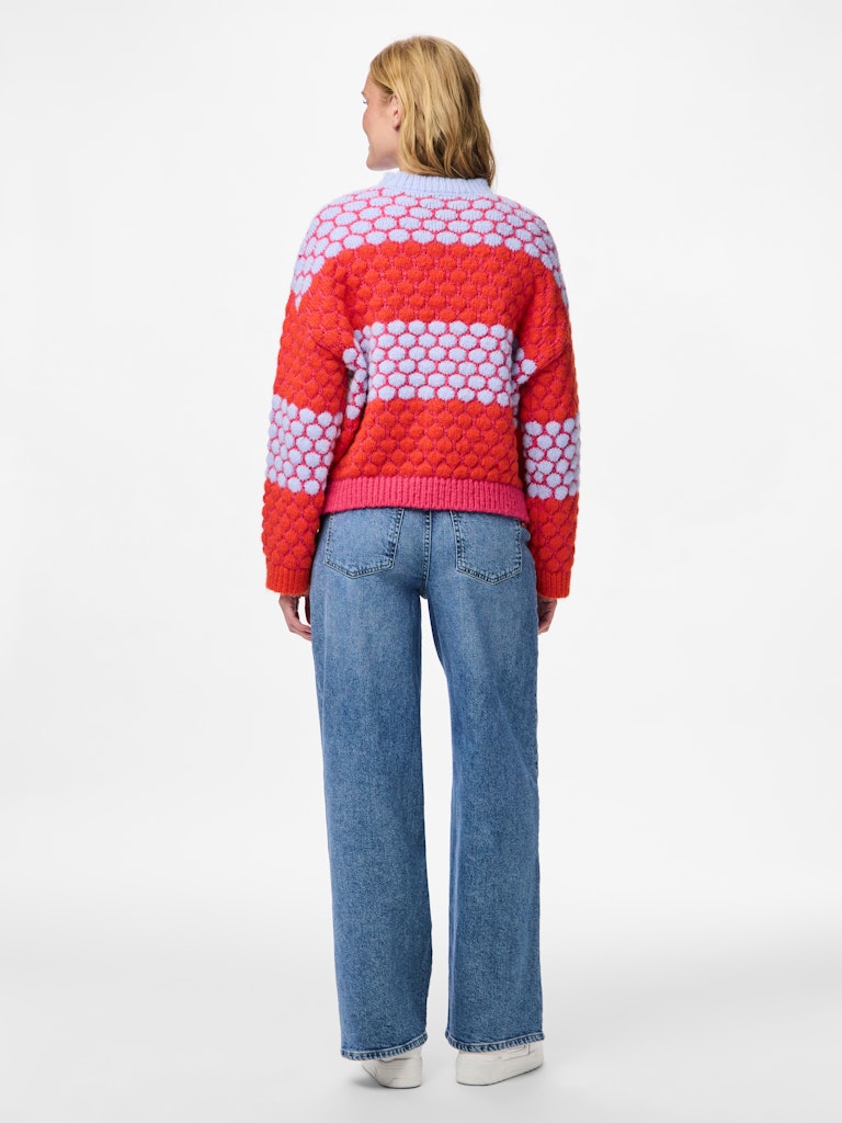 Person wearing a red and white patterned sweater with blue jeans on a white background
