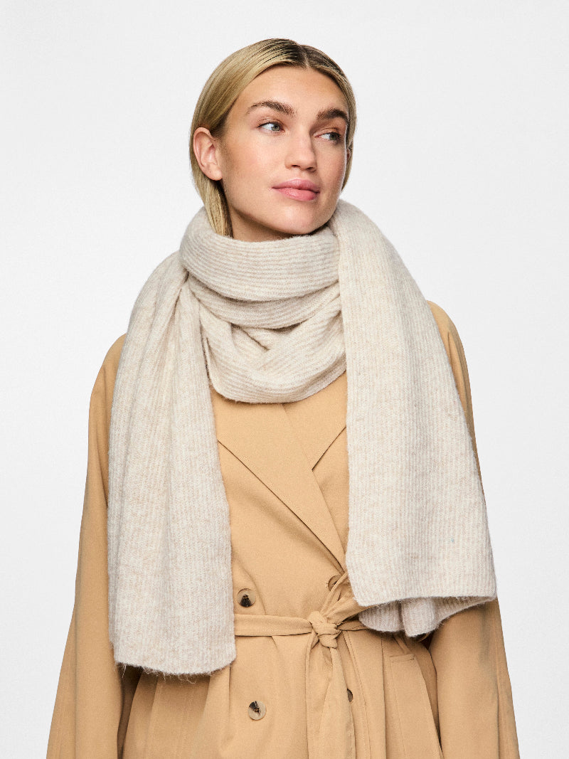 Woman wearing a beige scarf and coat on a white background
