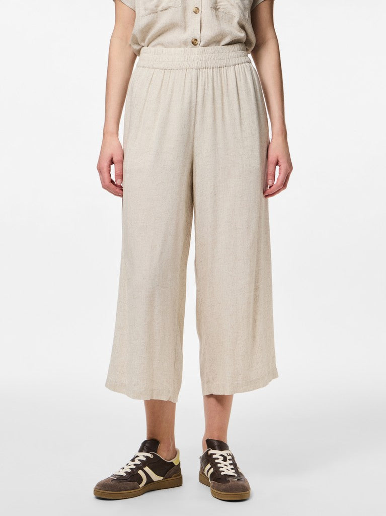Person wearing beige wide-leg pants on a white background