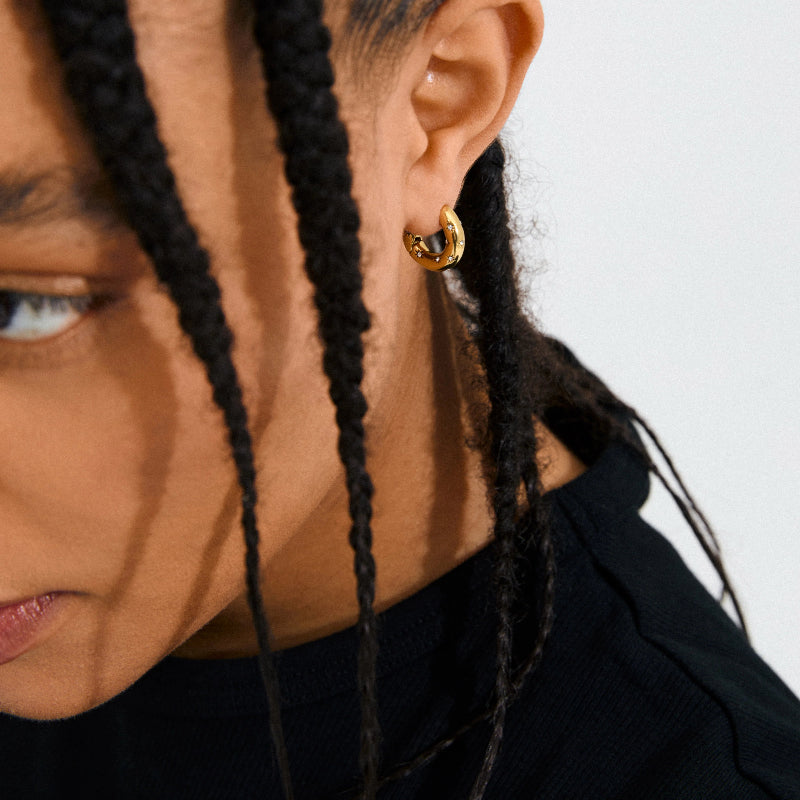 Close-up of a person wearing Pilgrim Nevaeh Earrings Gold-platedwith a neutral background