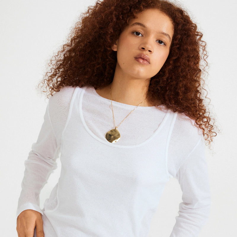 Woman wearing a white long-sleeve top with a Pilgrim Sparkle Necklace Gold-plated on a plain background