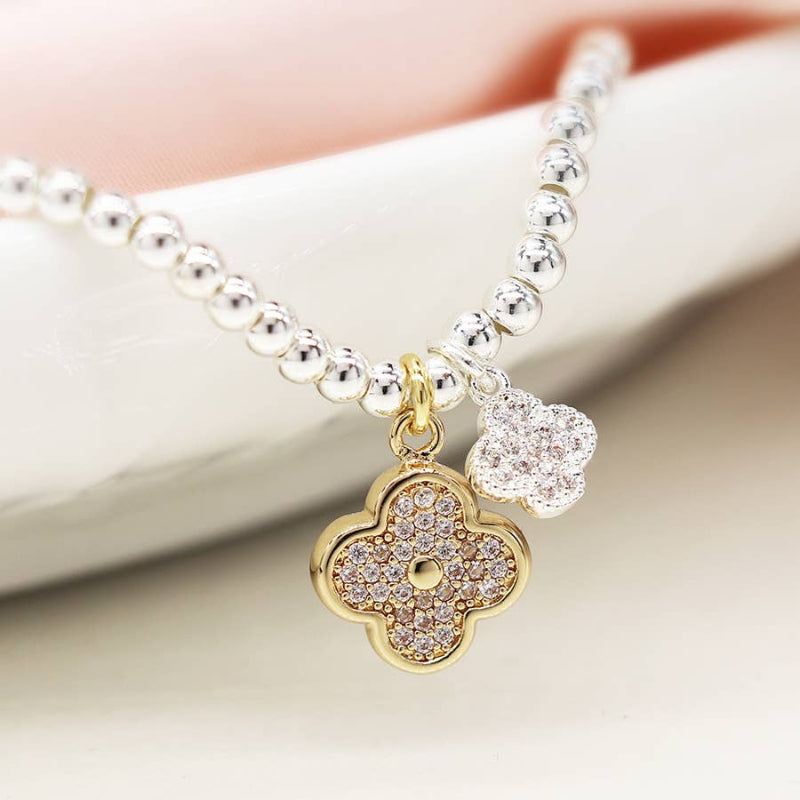 Bracelet with a gold clover charm and silver bead on a white background