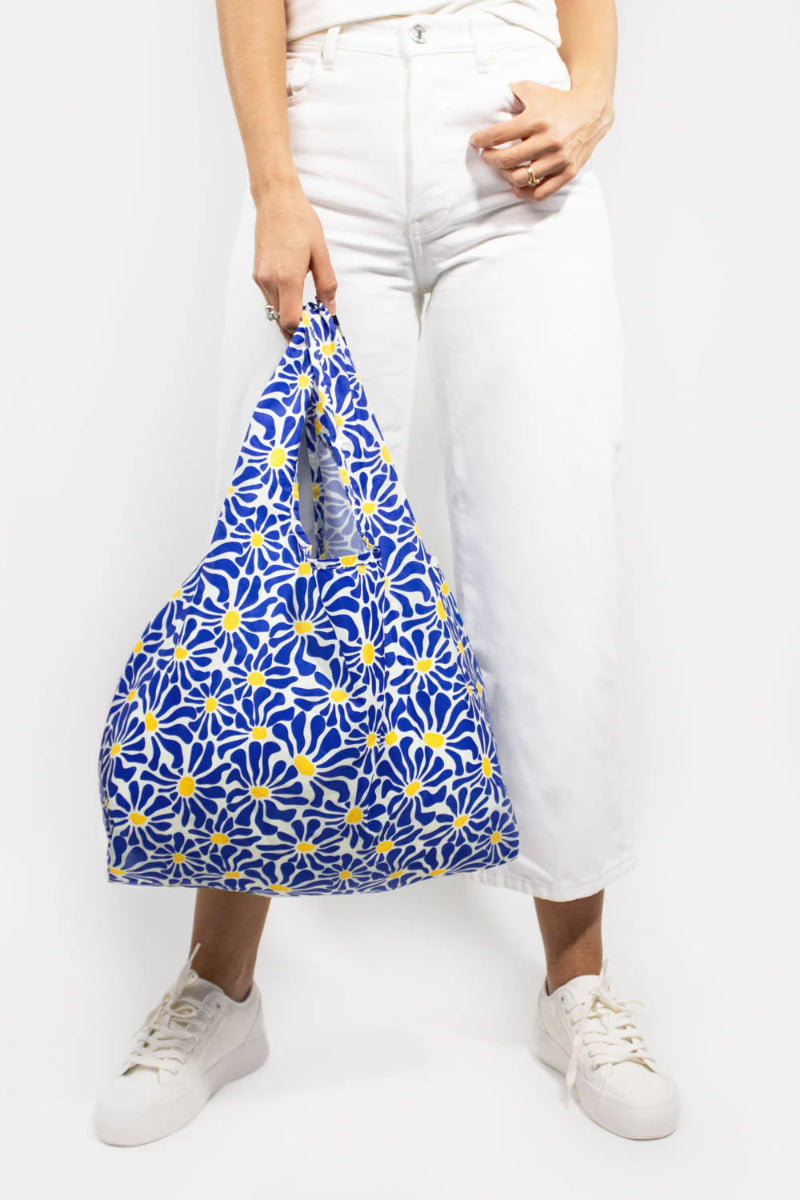 Person holding a blue floral-patterned bag against a white background
