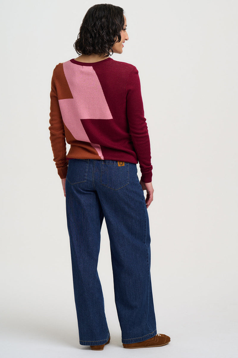 Person wearing a colorful sweater and blue jeans on a white background