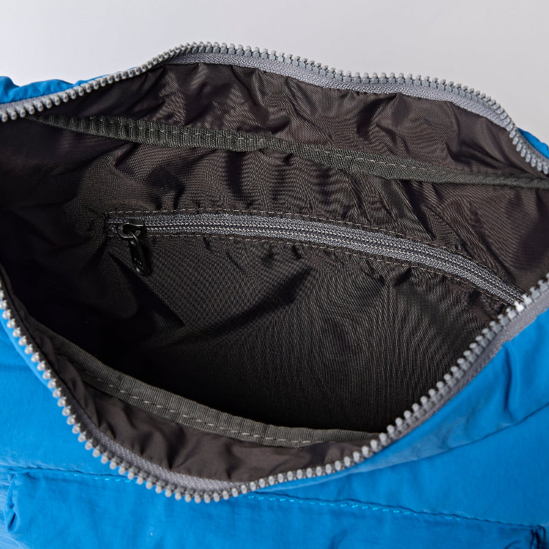 Close-up of a blue Roka Belize with a zipper open, showing black interior lining.