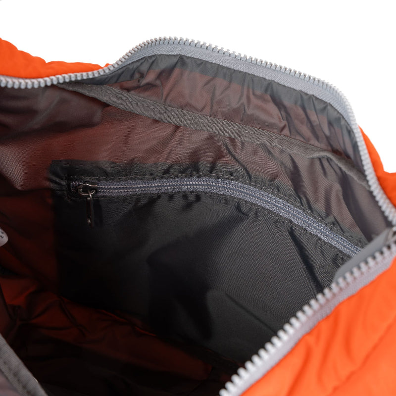 Close-up of an orange and gray backpack interior with zippers.